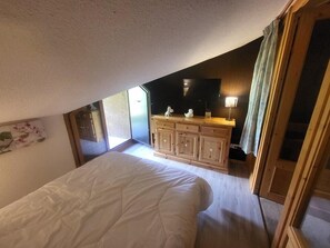 Quarto com uma cama, cômoda de madeira, espelho e janela.