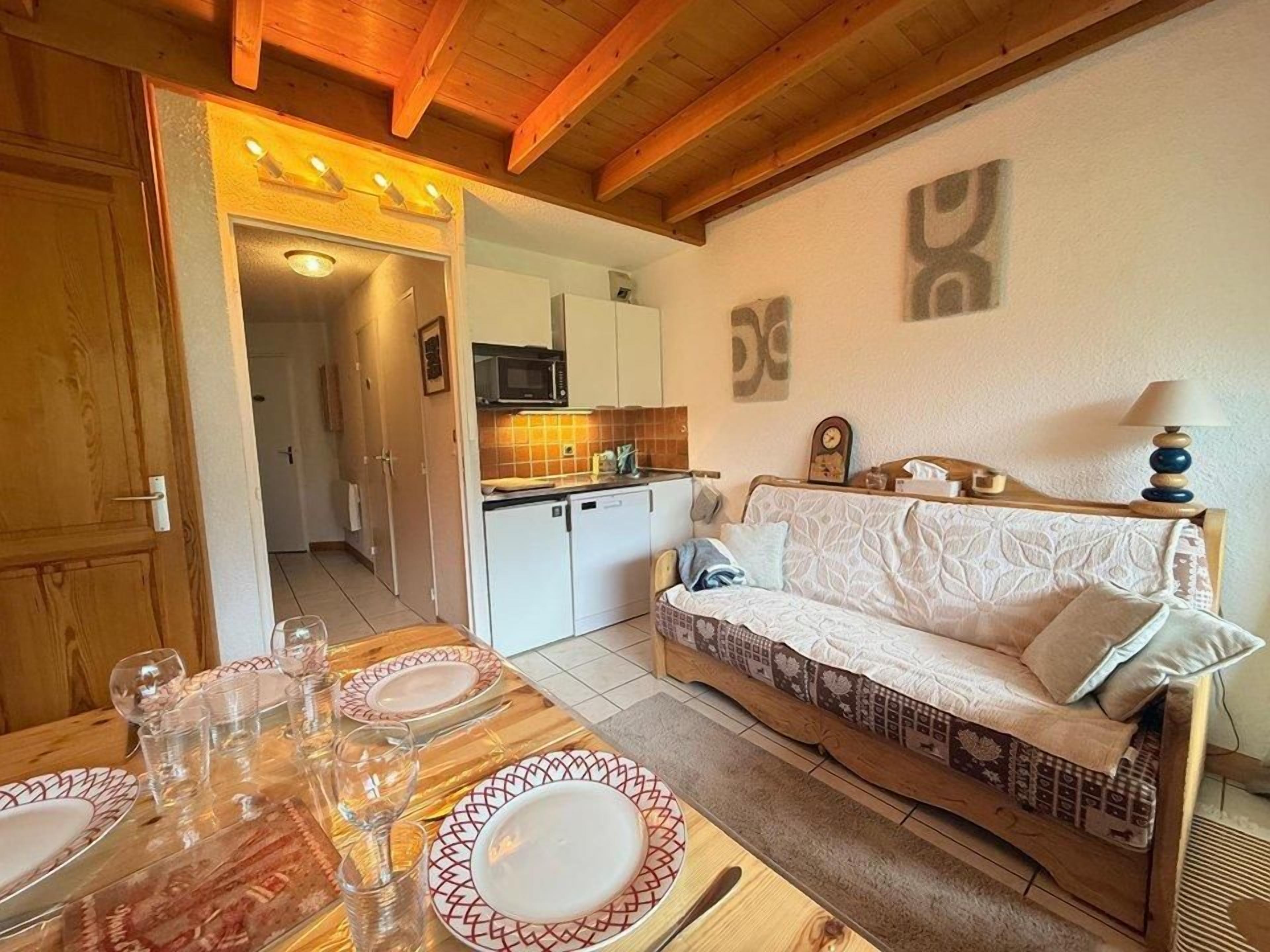 Ein gemütliches Wohnzimmer mit einer Couch, einem Esstisch für vier Personen und einer Küche im Hintergrund.
