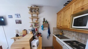 Una cocina compacta con armarios de madera, un microondas integrado y una estufa.