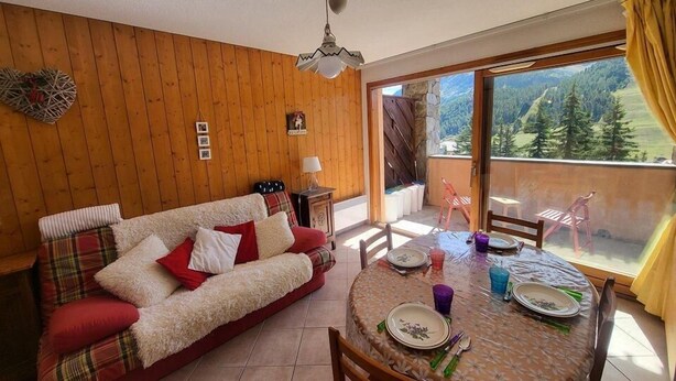 Una sala de estar acogedora con sofá, mesa de comedor y vistas a un paisaje montañoso a través de un ventanal corredero.