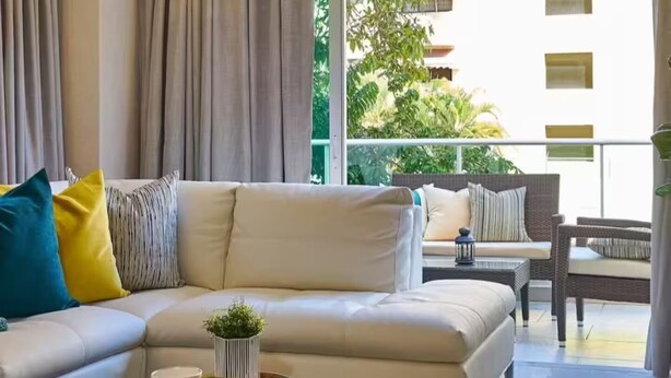A modern living room with a sofa, a round coffee table, and a view of greenery outside.