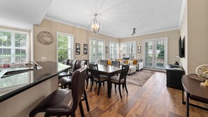 A spacious living room with a dining area, large windows, and a high ceiling. - Condo Near Pool and Attractions (Kissimmee)