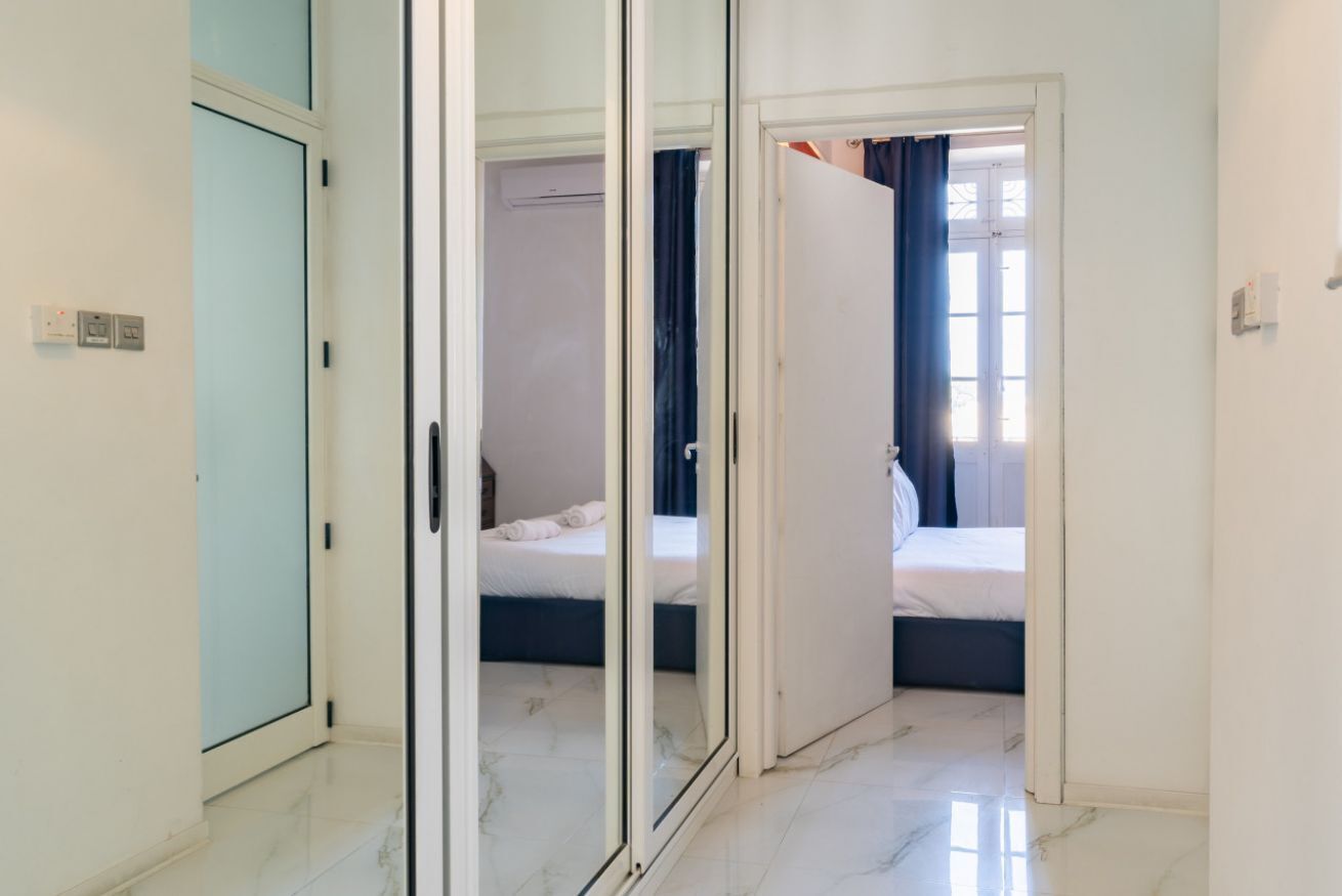 Une chambre d’hôtel comprenant un lit, une armoire et une porte coulissante donnant sur une autre pièce.