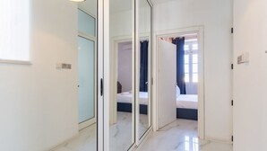 Ein modernes Hotelzimmer mit einer großen Schiebeglastür zu einem Schlafbereich, einem Badezimmer mit Duschvorhang und einem Marmorboden.