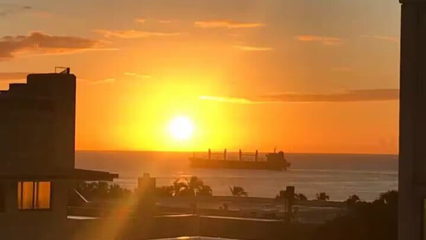 A sunset over a body of water with a cargo ship in the distance. - Atractivo loft (Santo Domingo)