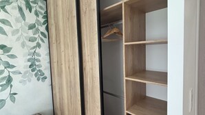 Um quarto com uma cama, um guarda-roupa com espelho e um armário com prateleiras.
