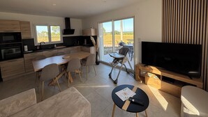 Cozinha moderna com área de refeições, televisão e vista para o exterior.