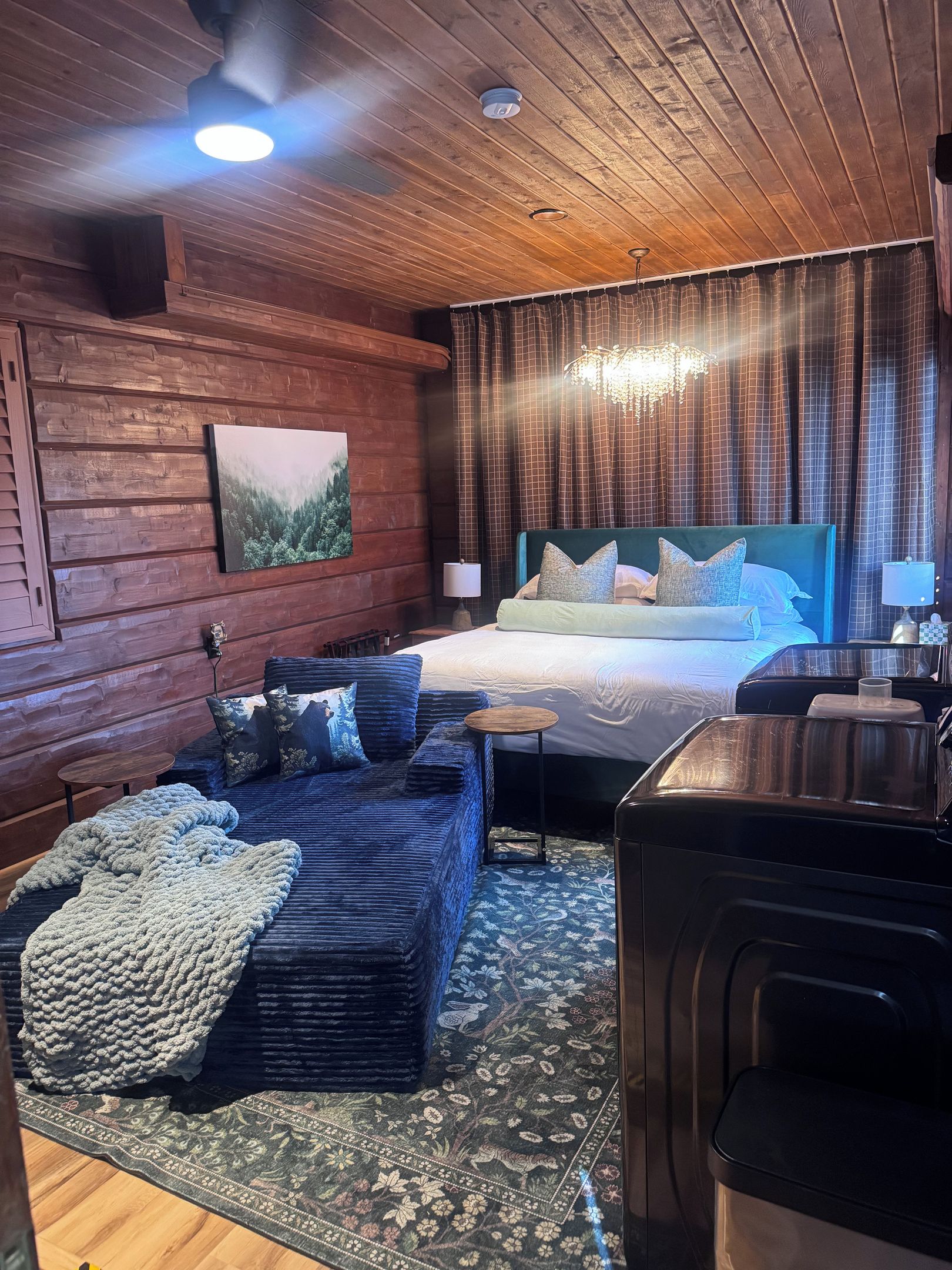 A cozy room with a bed, a sofa, a small table, and a heater.