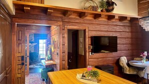 A wooden interior with a dining table, chairs, and a TV mounted on the wall. - Romantic Winter Escape/Hot tub in Heaven (Pine)