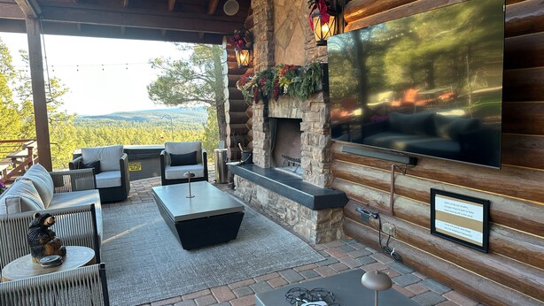 A cozy outdoor seating area with a stone fireplace, a flat-screen TV, and a scenic view of the mountains. - Romantic Winter Escape/Hot tub in Heaven (Pine)
