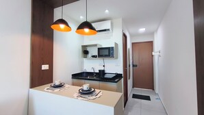 Una cocina moderna con microondas, pileta y dos lámparas colgantes.
