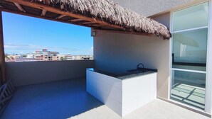 Un balcón con techo de paja, un lavamanos integrado y vistas de la ciudad.