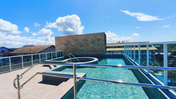 Una piscina en la azotea con un muro de piedra y barandillas de vidrio.