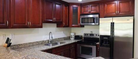 A kitchen with granite countertops, stainless steel appliances, and wooden cabinets.