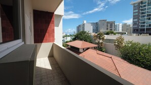 Uma varanda com vista para um horizonte urbano, incluindo edifícios e um céu claro.