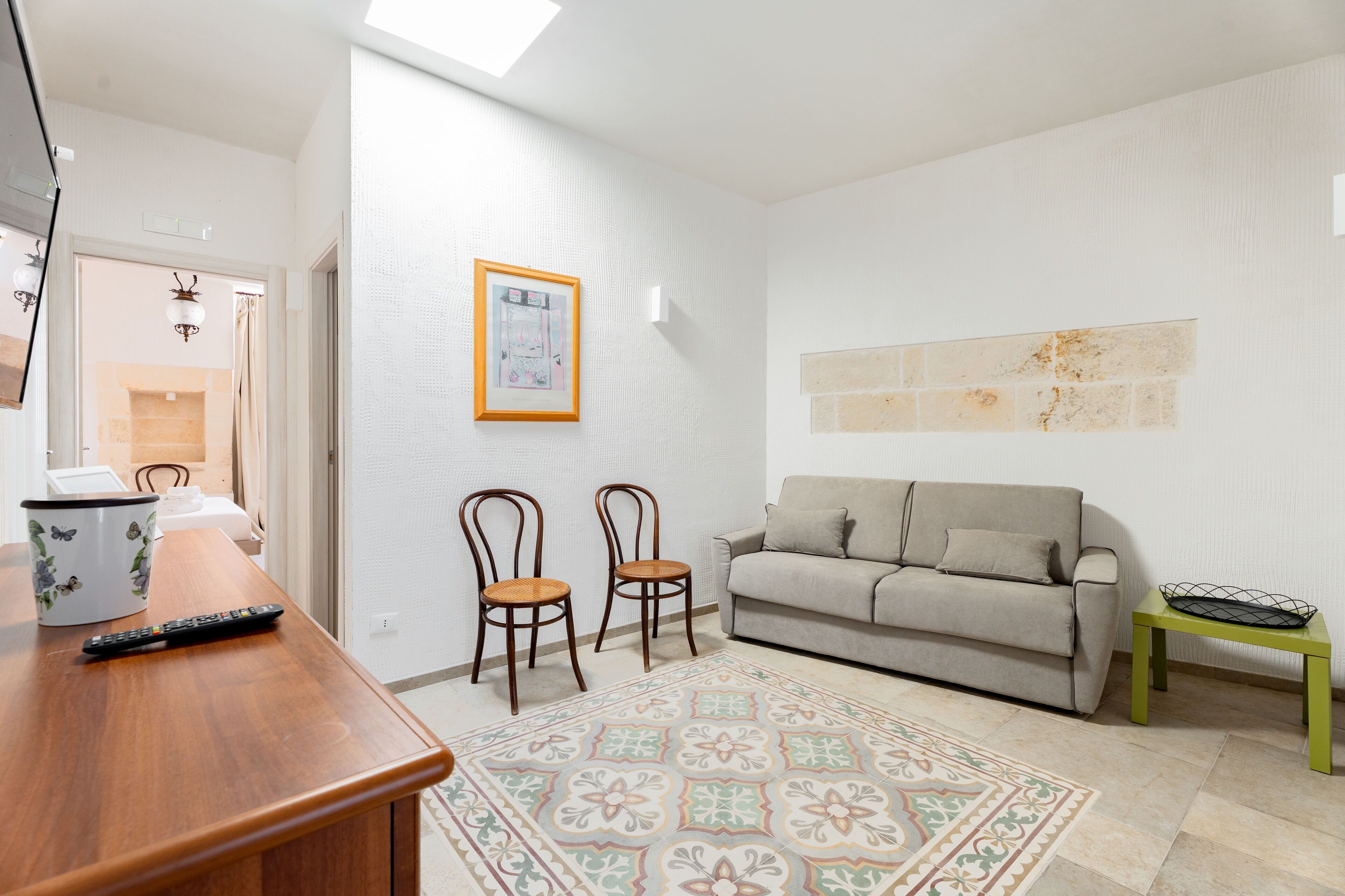 A living room with a sofa, two chairs, a coffee table, a rug, and a framed picture on the wall.