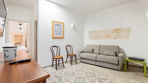 Ein Wohnzimmer mit einer Couch, zwei Sesseln, einem Couchtisch, einem Teppich und einem gerahmten Bild an der Wand.