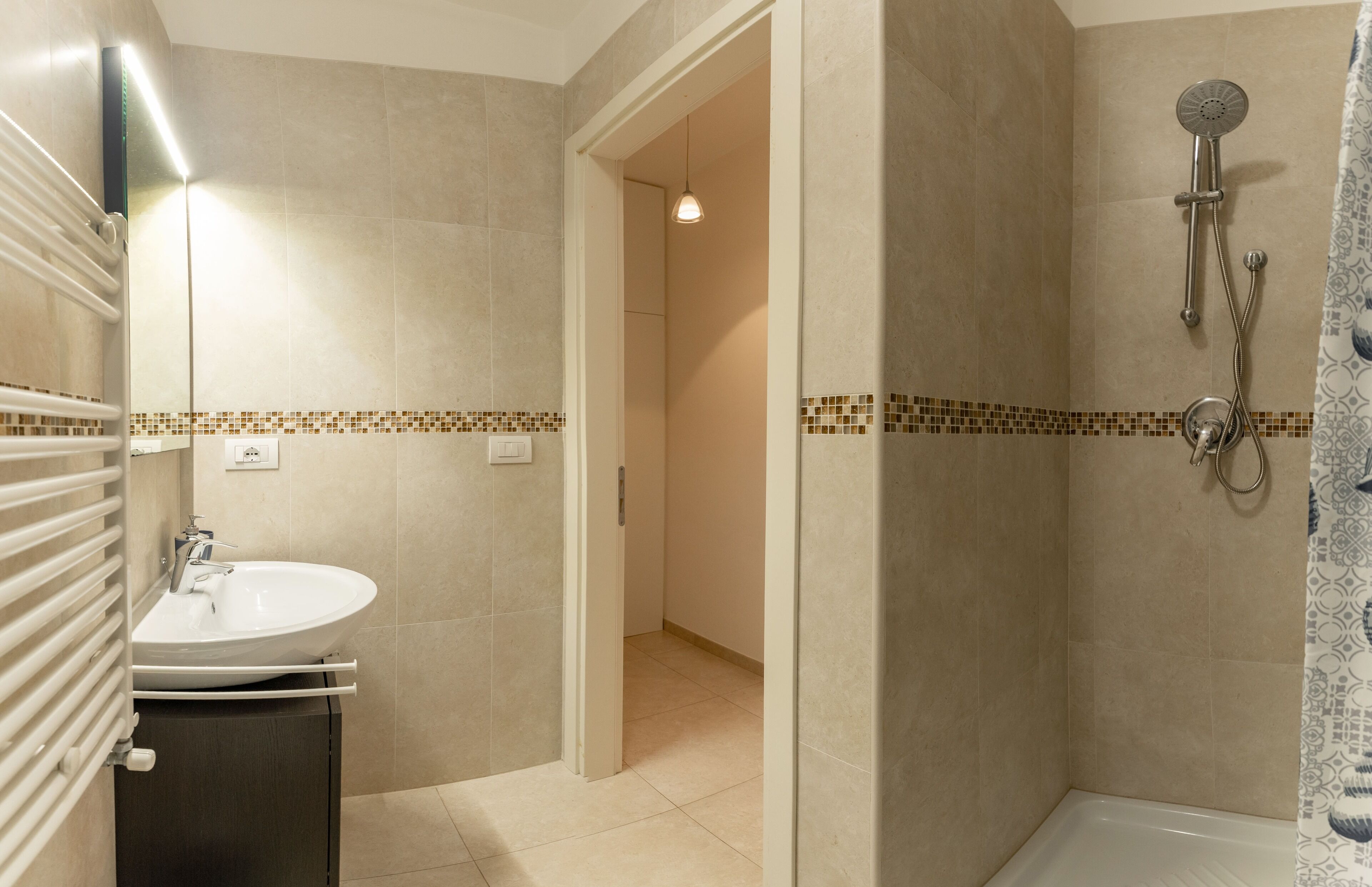 A bathroom with a sink, shower, and tiled walls.