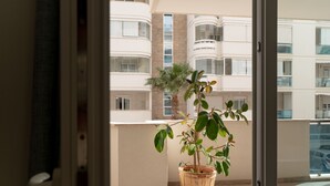 A balcony with a potted plant, a view of a multi-story building, and a door frame. - Alba di mare by Monholiday (Monopoli)