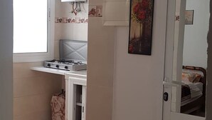 A compact kitchen with a gas stove, a small cabinet, and a window. - Studio Nahid 3rd floor free wifi (Tanger)