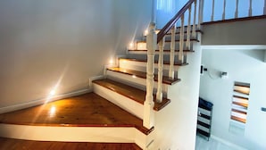Una escalera de madera con barandillas blancas que sube a un piso superior.