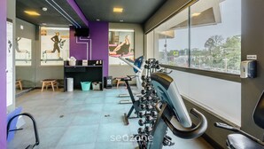 Ein Fitnessraum mit Trainingsgeräten, Laufband und Fenster mit Blick ins Freie.