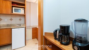 Eine kleine Küche mit Kühlschrank, Mikrowelle, Kaffeemaschine und Mixer auf einer Holzauskład.