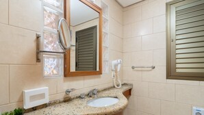 Ein Badezimmer mit Marmorwaschtisch, Spiegel, Haartrockner und Handtuchhalter.