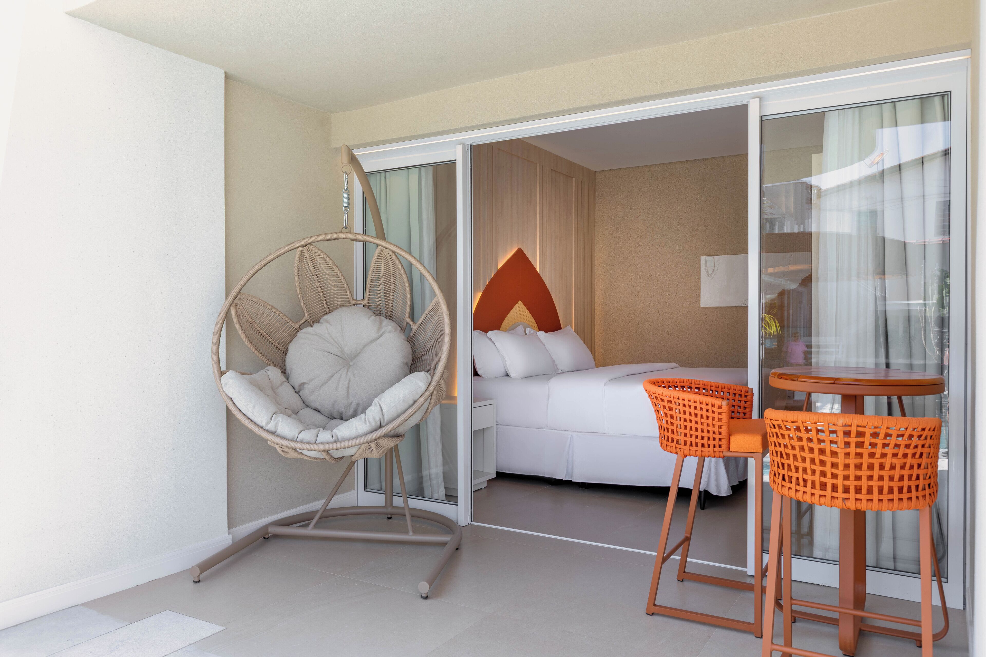 A hotel room with a bed, a hanging chair, and a table with chairs.