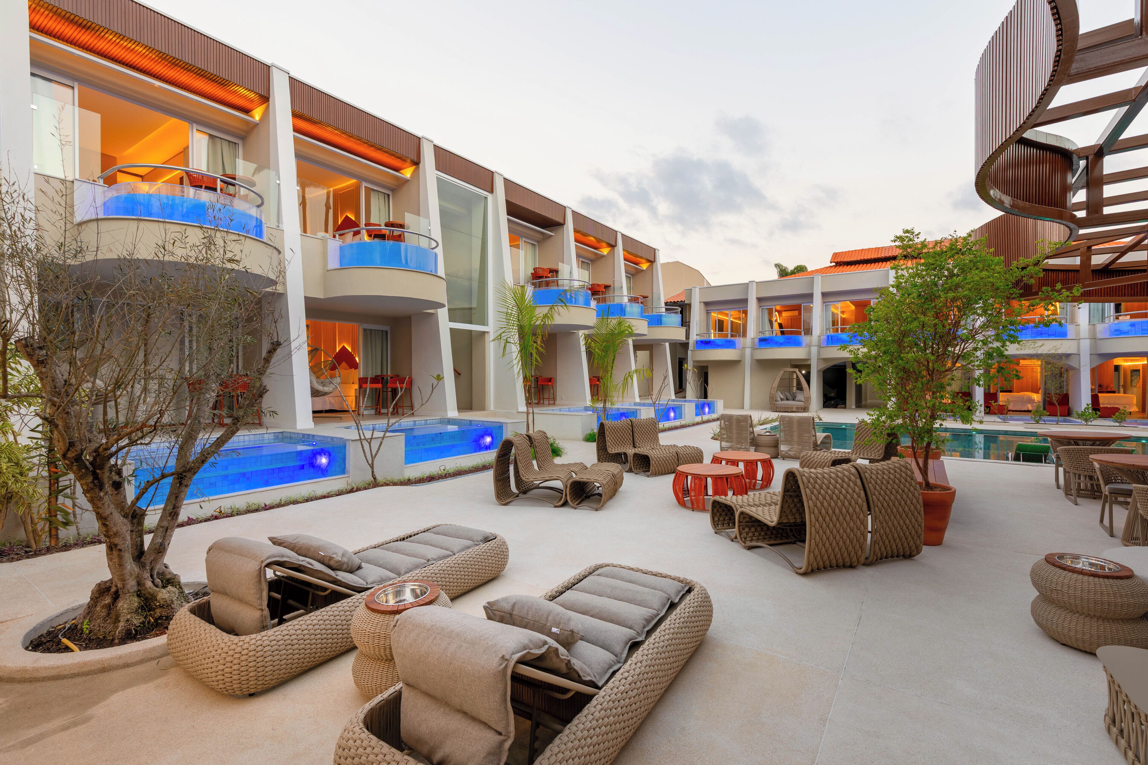 A hotel courtyard with outdoor seating, a pool, and multiple balconies.