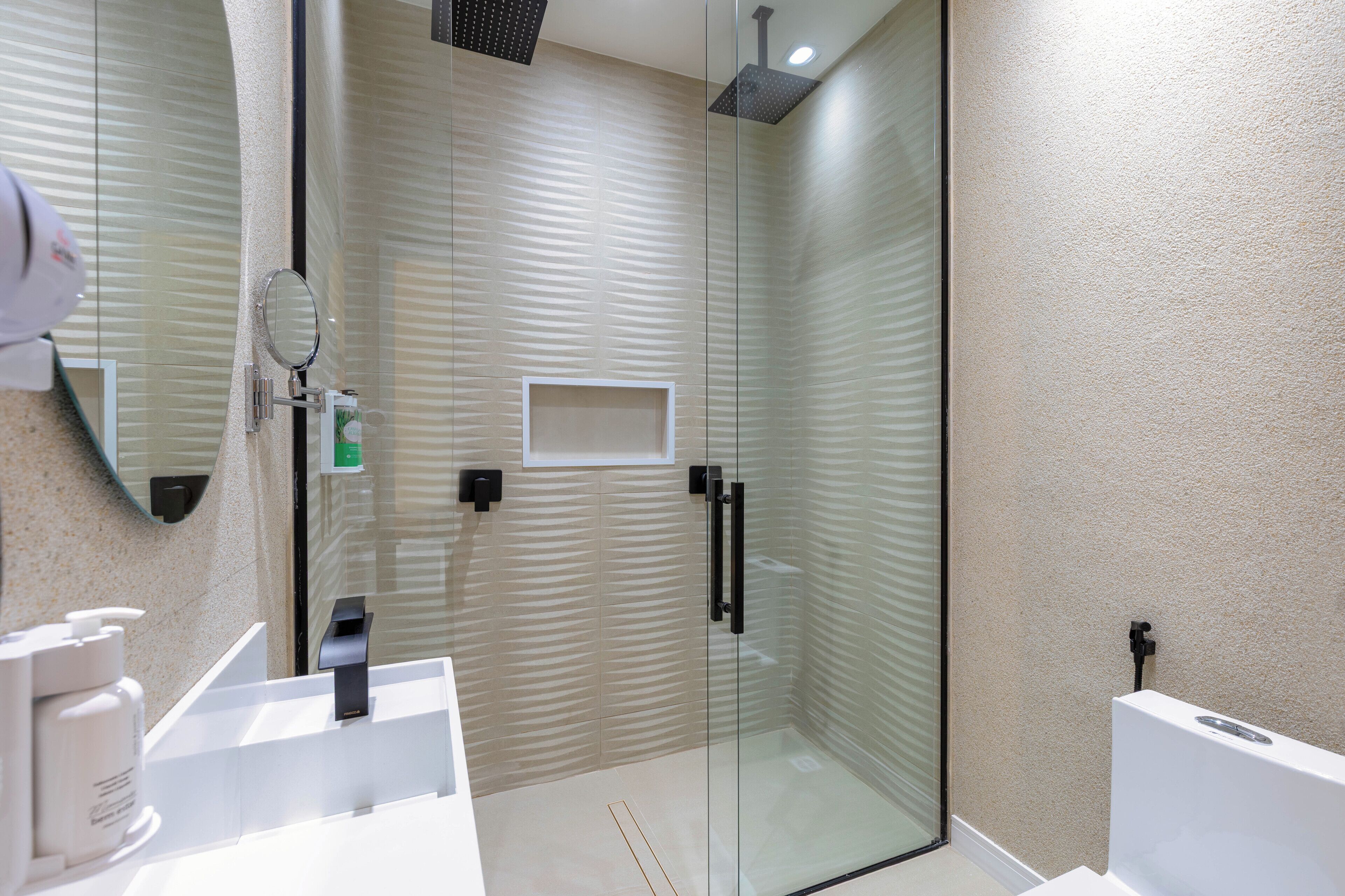 A modern bathroom with a glass shower enclosure, a white sink, and a mirror.