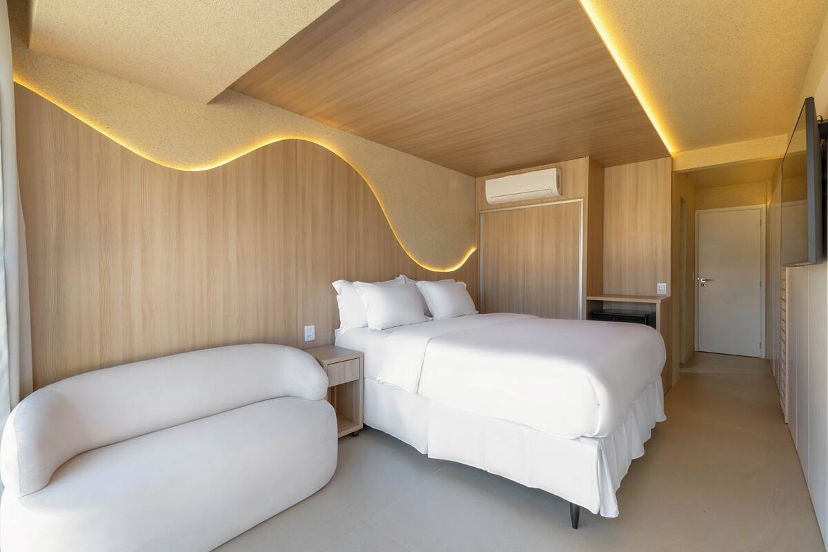 A modern bedroom with a curved ceiling, a double bed, a bedside table, and a wardrobe.