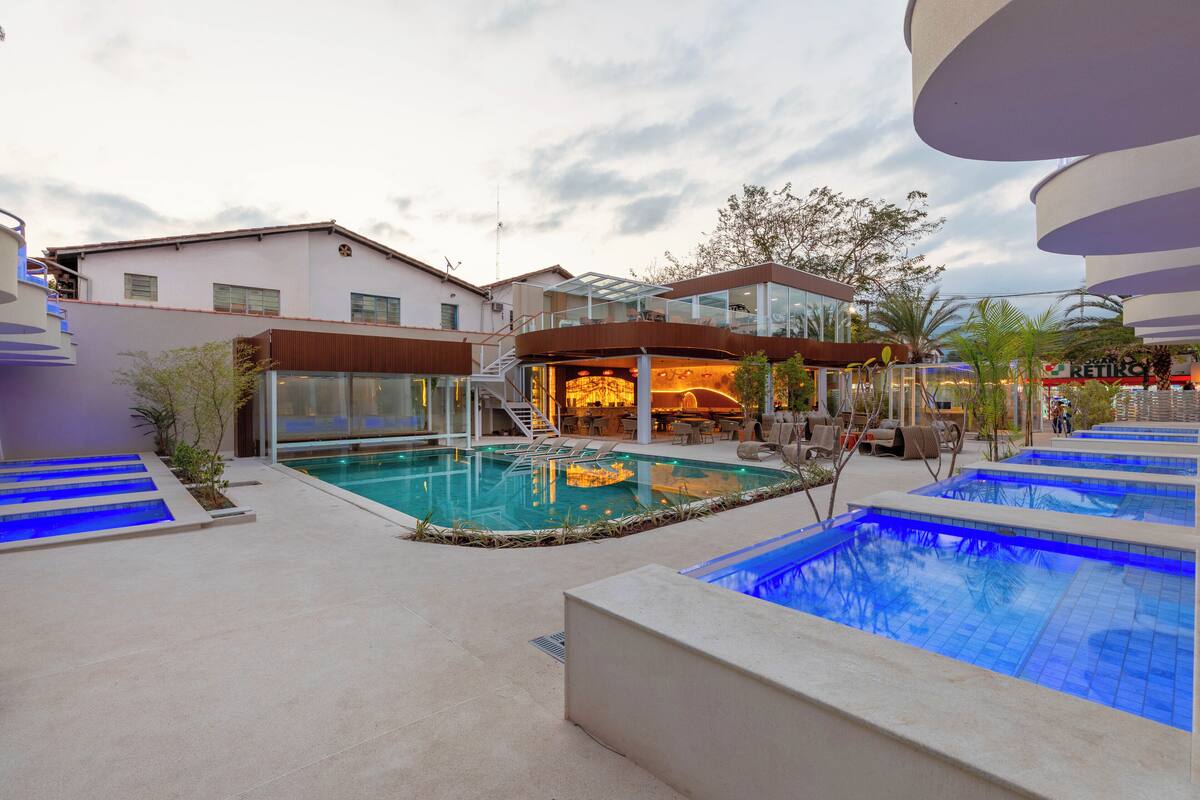 A modern outdoor pool area with a glass-enclosed bar and lounge seating.