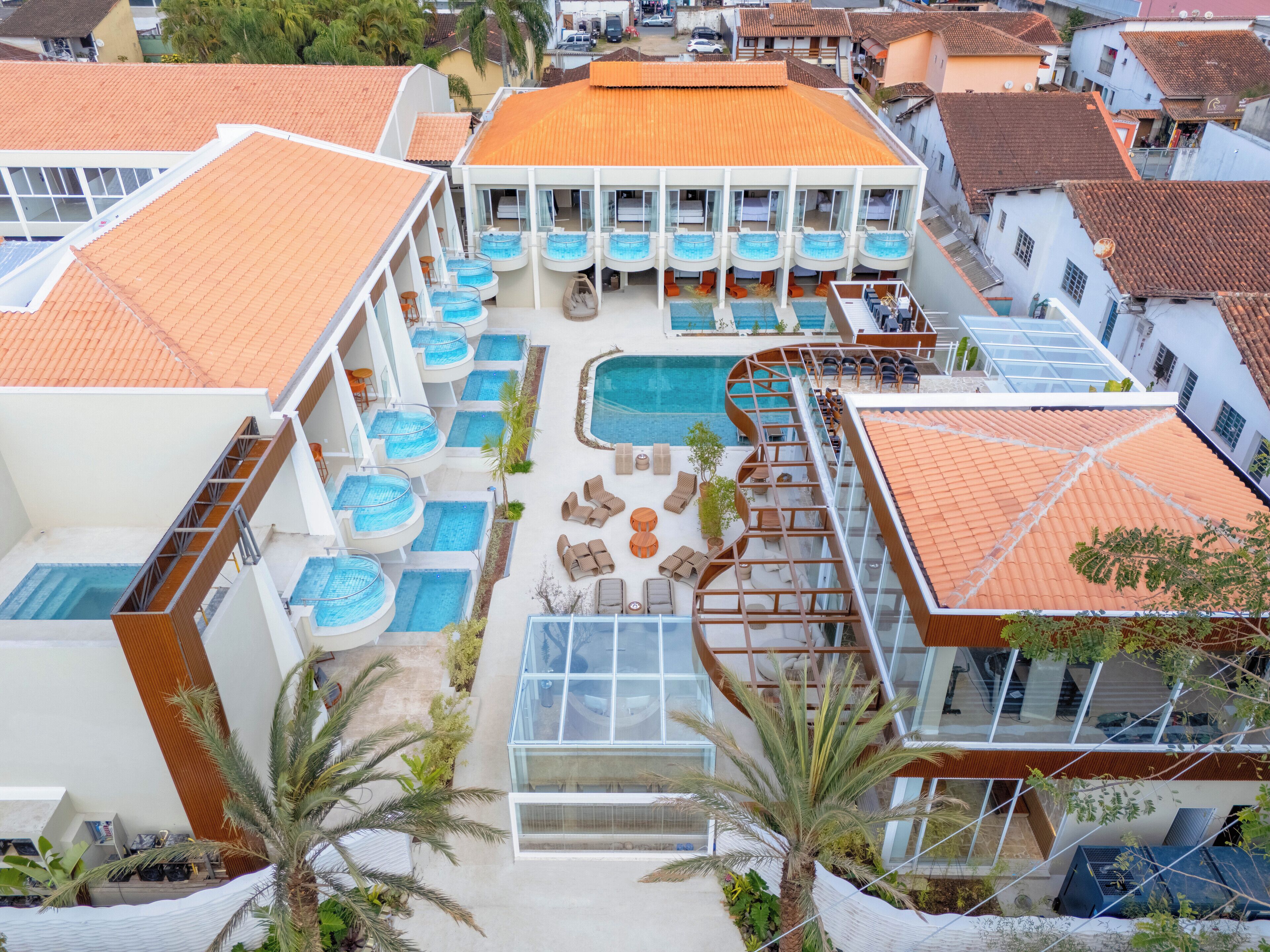 A hotel with multiple swimming pools, outdoor seating areas, and a central pool.