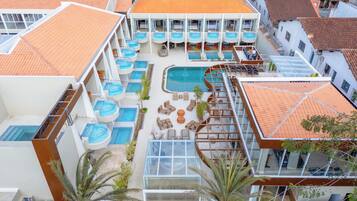 A hotel with multiple swimming pools, outdoor seating areas, and a central pool.