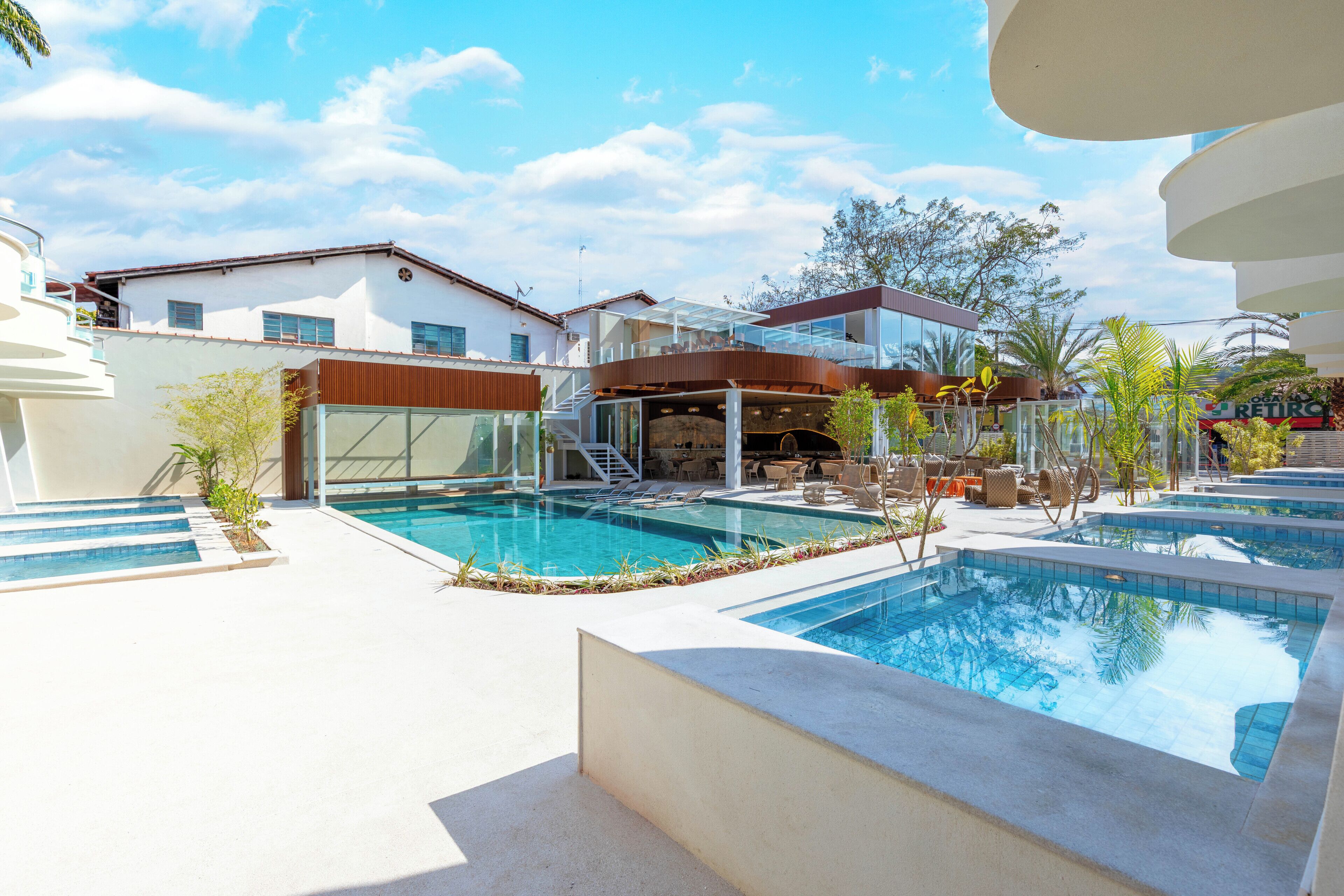 A pool area with multiple pools, lounge chairs, and a covered seating area.