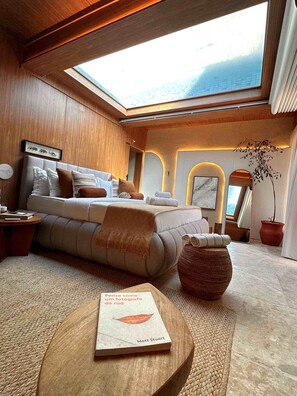 A modern interior with a sofa, a book on a round table, and a skylight. - Sdesign Paraty Hotel (Paraty)