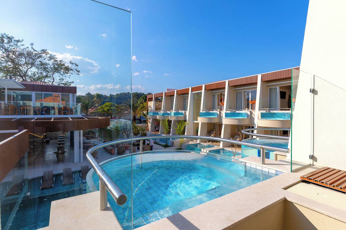 A hotel with a pool area, multiple balconies, and a view of the surrounding landscape.