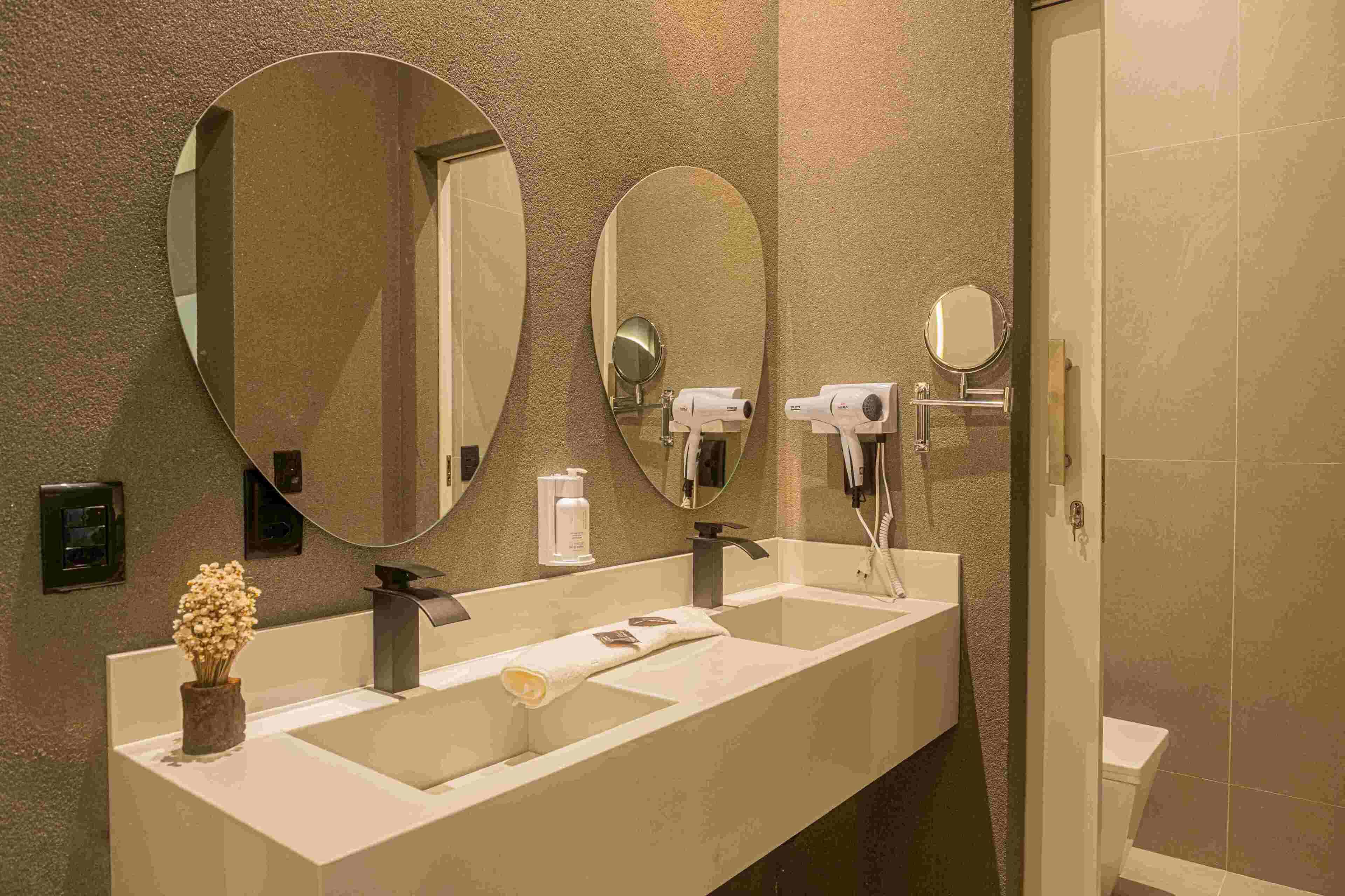 A bathroom with two sinks, a large mirror, a towel, and a hairdryer.