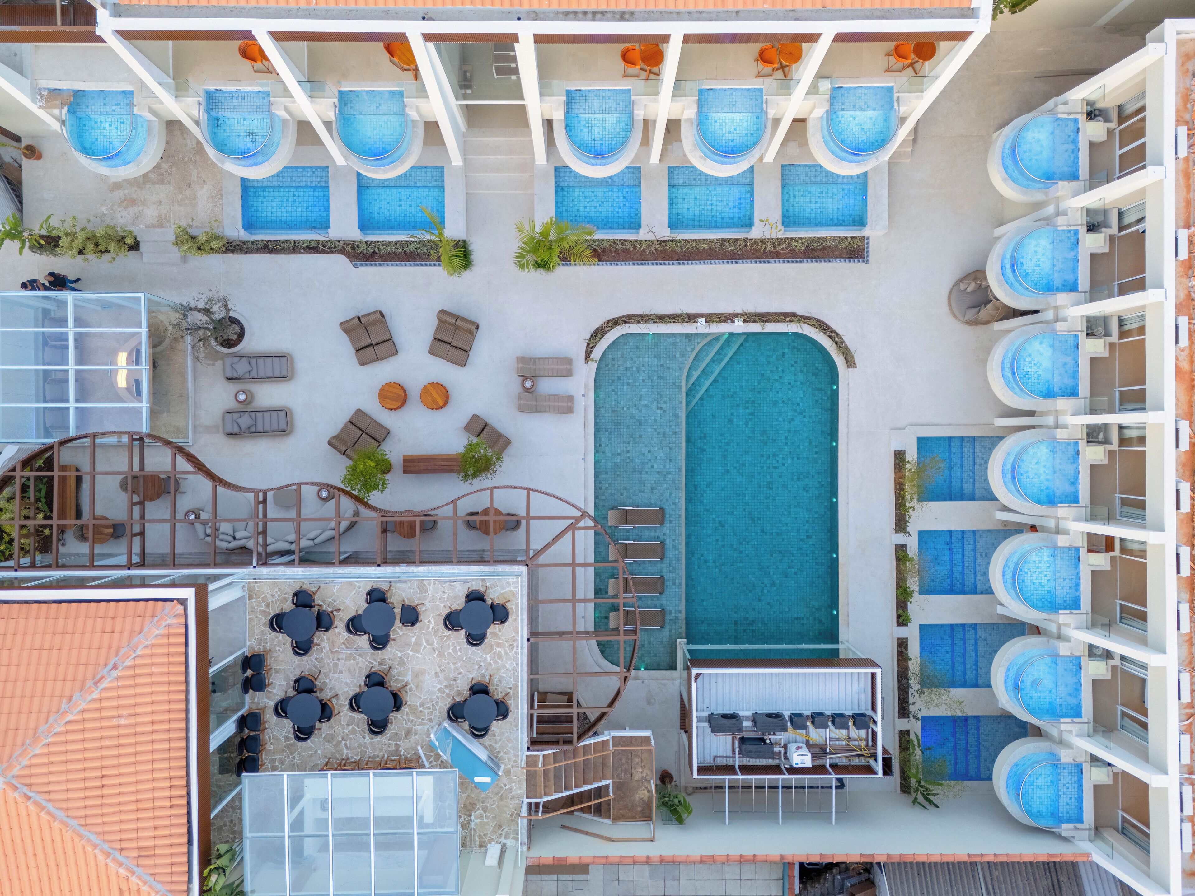 Ein Poolbereich auf dem Dach mit mehreren Pools, Liegestühlen und Tischen.