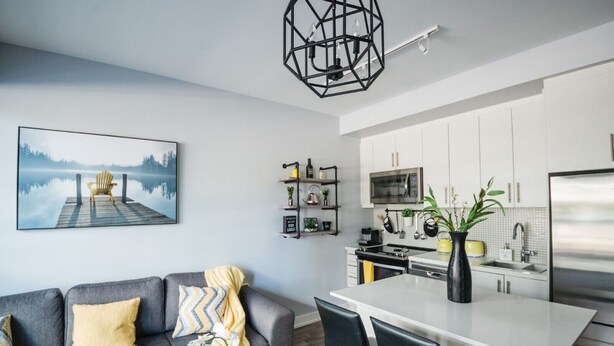 Una cocina moderna con armarios blancos, un refrigerador de acero inoxidable y un comedor con una isla blanca.