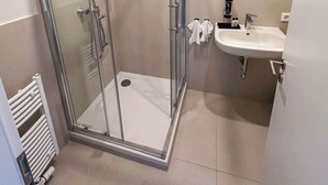 Une salle de bain moderne avec une douche à parois de verre, un lavabo avec un miroir et un porte-serviettes.