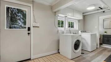 A laundry room with a washing machine, dryer, and a door with a window.
