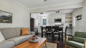 A living room with a sofa, a coffee table, and a dining area with chairs and a table.