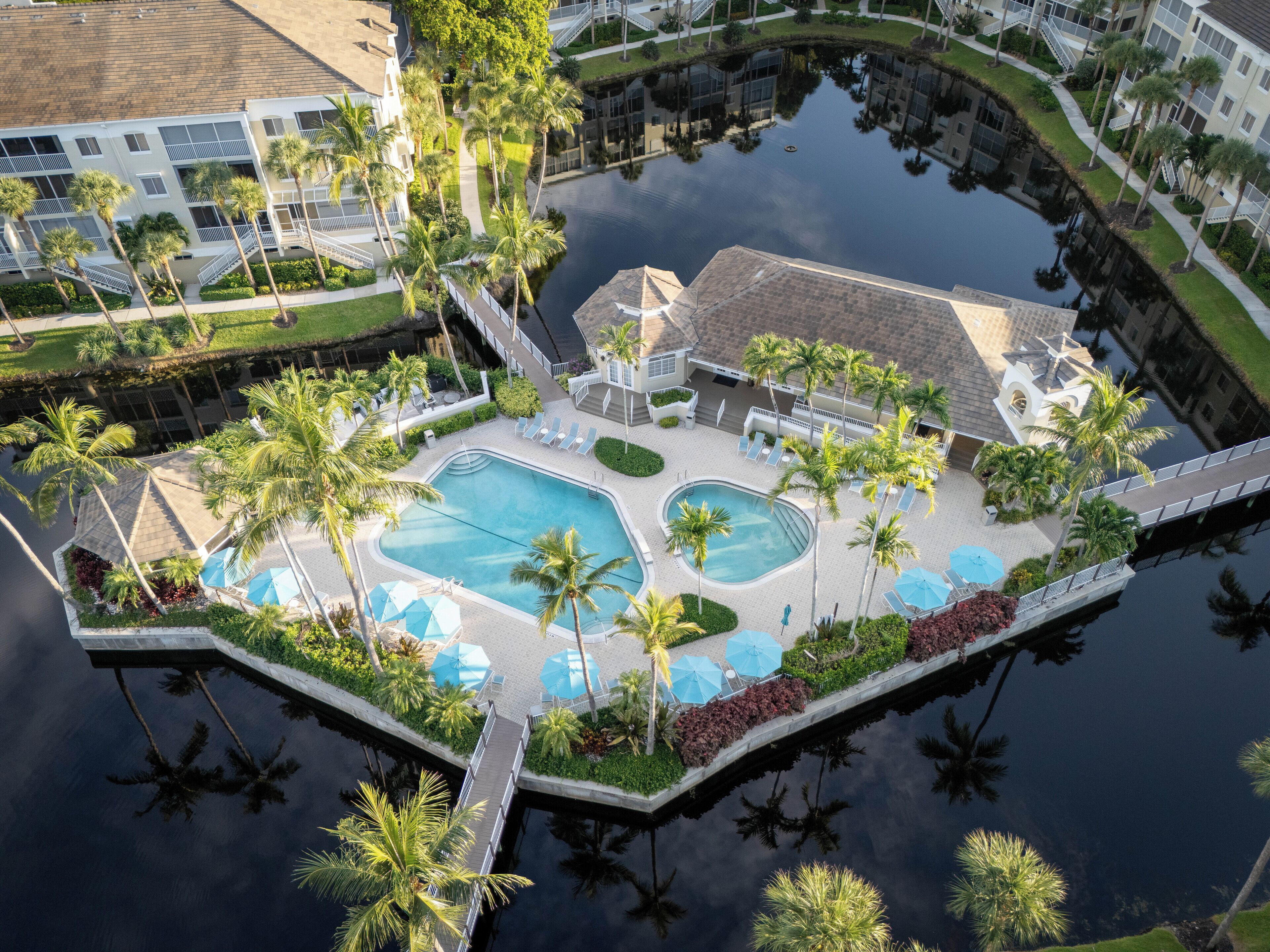 Oversigtsbillede af et resort med flere swimmingpools, palmer og en vandkanal.