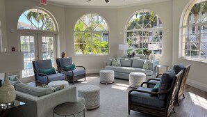 A spacious, well-lit room with large arched windows, comfortable seating, and a ceiling fan. - Spacious 3-bedroom condo minutes from beach with access to resort-like amenities (Naples)