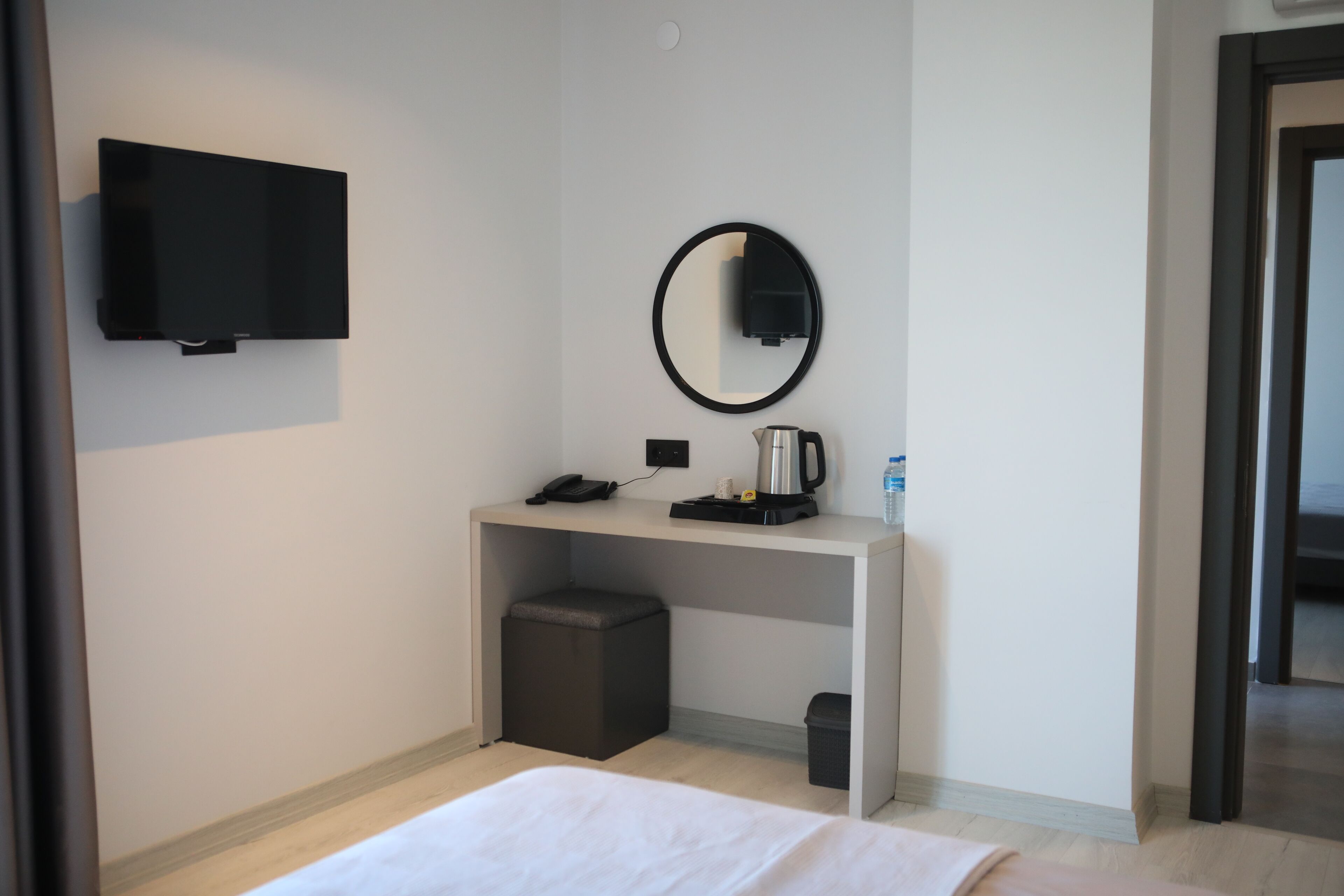 Una habitación de hotel con una cama, un escritorio con cafetera, un teléfono y un televisor fijado a la pared.