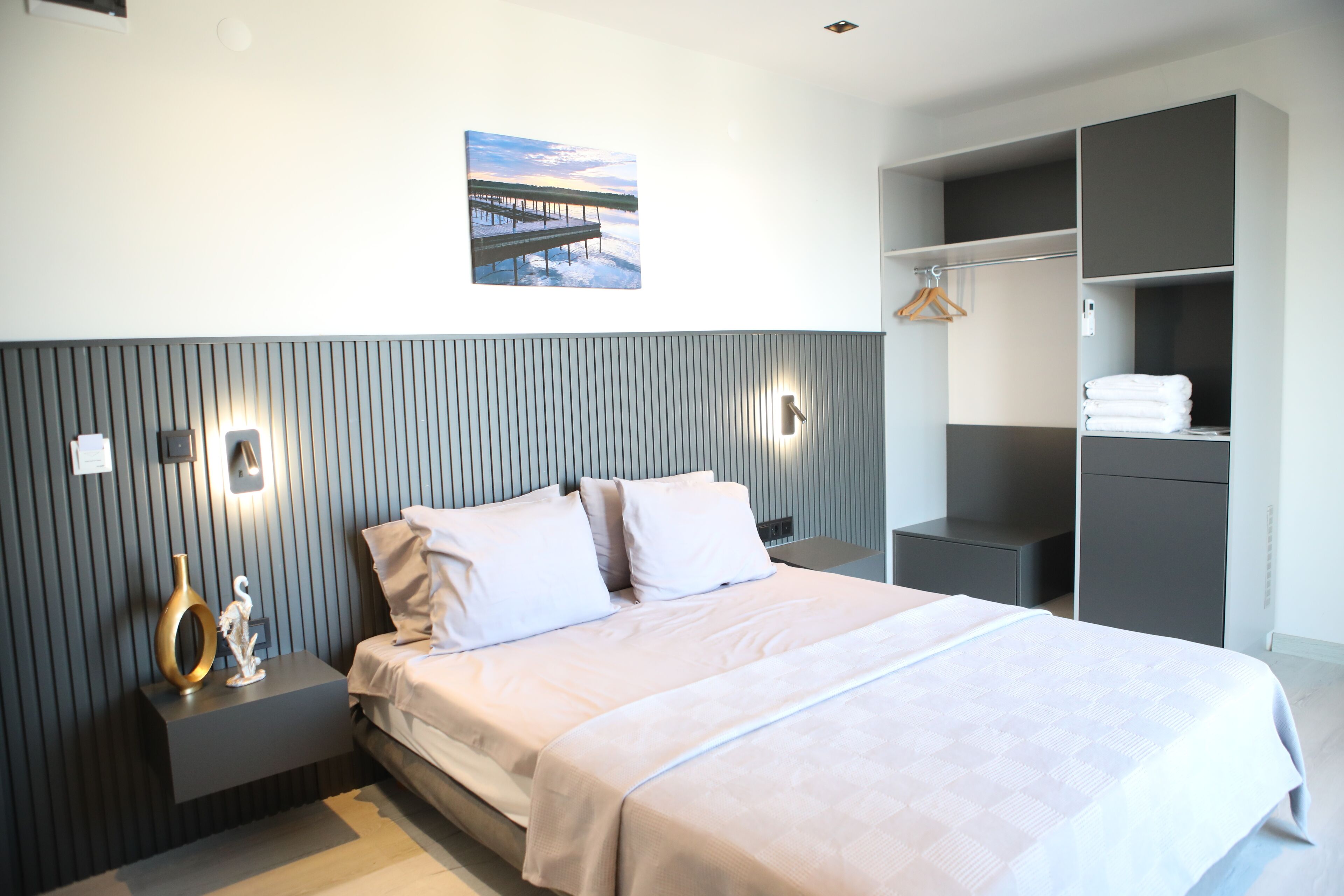 Une chambre à coucher moderne, avec un lit, des tables de chevet, une armoire et un tableau accroché au mur.