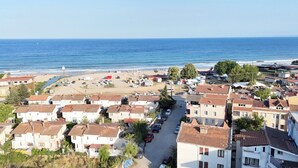 A coastal town with residential buildings, a beach, and a clear view of the sea. - Koç Guest House (Demirkoy)