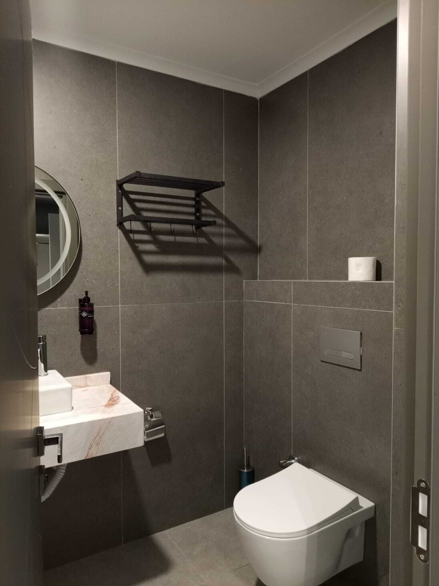 Een moderne badkamer met een wit wastafelmeubel, een toilet en een handdoekhouder.